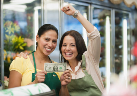 Hispanic women in florist shop holding first dollar bill